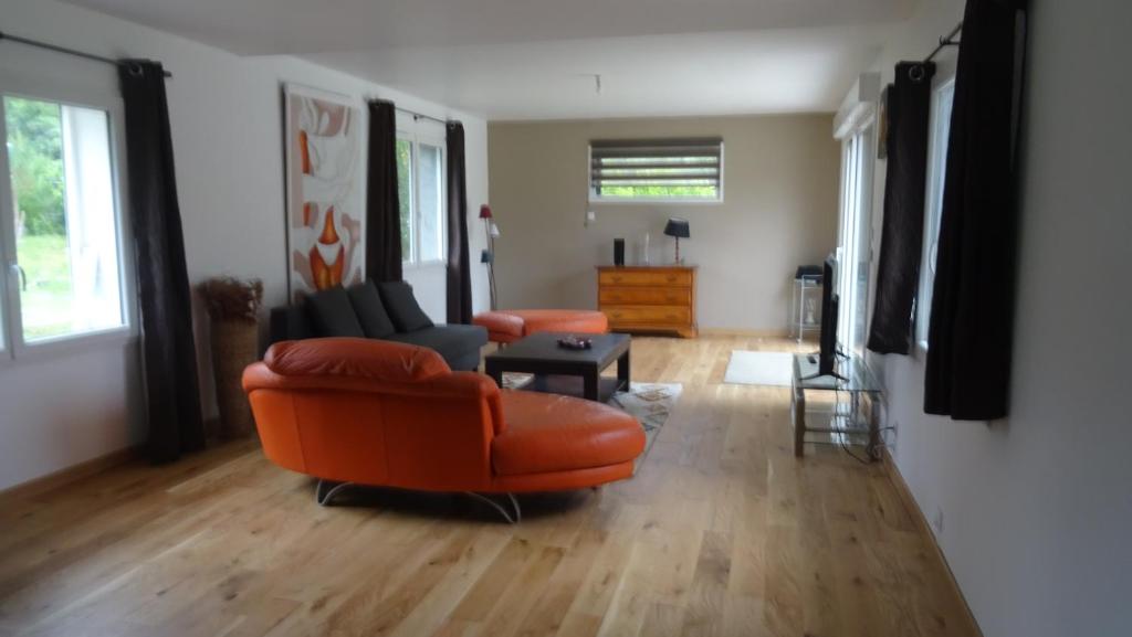 a living room with an orange chair and a couch at Pinede in Labenne