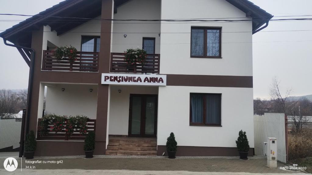a white house with a sign that reads pueblo amaina at Pensiunea Anna in Poplaca