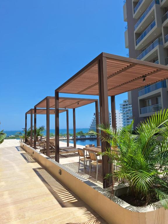 a pavilion with tables and chairs on a beach at Exclusivo apartasuite con terraza y vista al mar - Bello Horizonte in Santa Marta