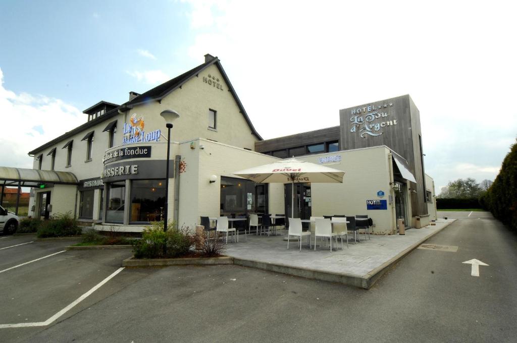 een gebouw met tafels en stoelen op een parkeerplaats bij Hôtel Le Saint Loup in Gembloux