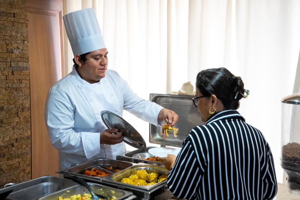 a chef preparing food for a woman in a kitchen at Hotel Presidente Internacional in Guayaquil