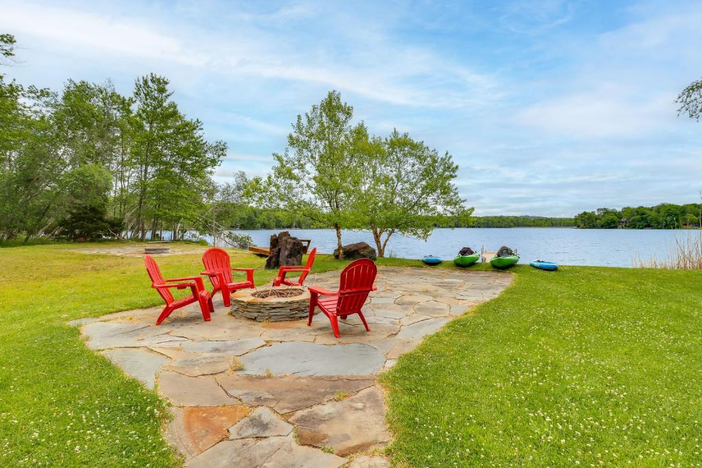 a group of red chairs sitting on a stone patio next to a lake at Lakefront Cabin: Kayaks, Paddle Boards & Fishing in Pocono Lake