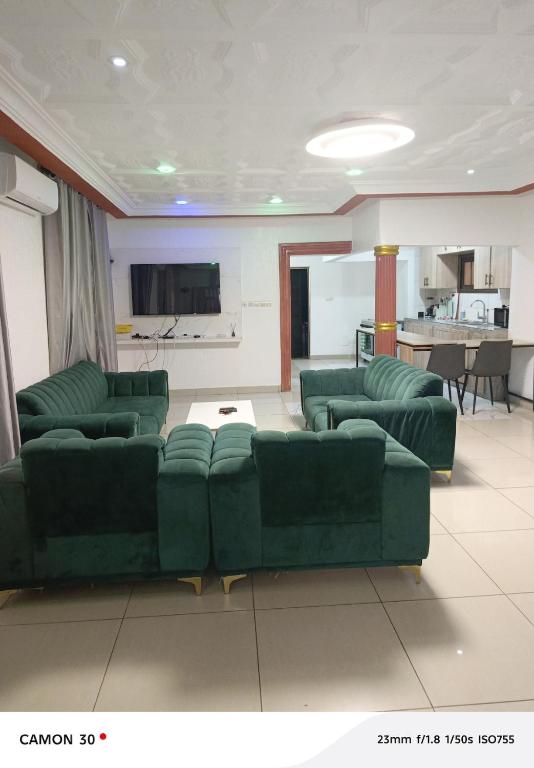 a living room with green couches and a kitchen at sea flower in Lomé
