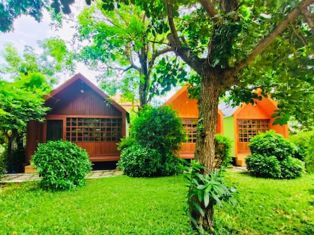 an orange house in the middle of a green yard at สวนไมตรีจิต รีสอร์ท Suan Maitrichit Resort in Ban Khlong Si
