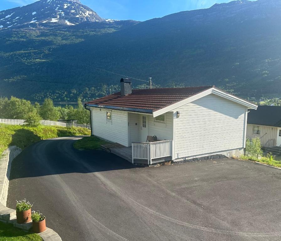 a small white house with a driveway in front of a mountain at Koselig hus i Beisfjord in Narvik