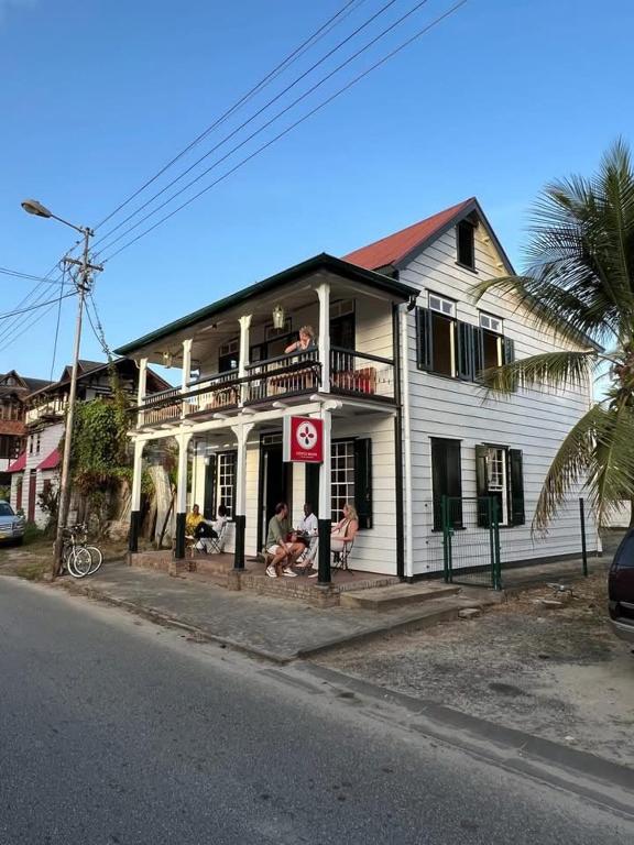 a white house with people sitting on a balcony at Coffee Mama Stay in Paramaribo