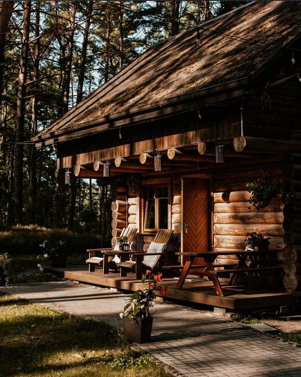 a log cabin with a table and chairs in front of it at Piparmētras in Mērsrags