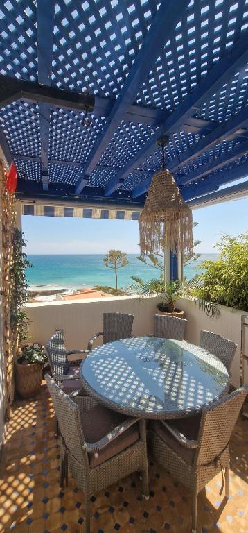 a patio with a table and chairs and the ocean at Tiguert serenity in Tiguert