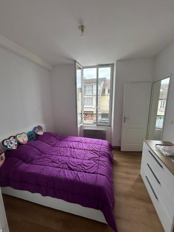 a bedroom with a purple bed and a window at De passage in Nemours