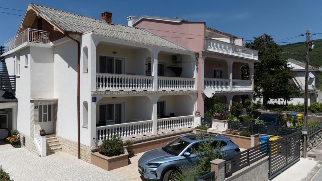 a house with a car parked in front of it at Apartmani Čeko in Selce
