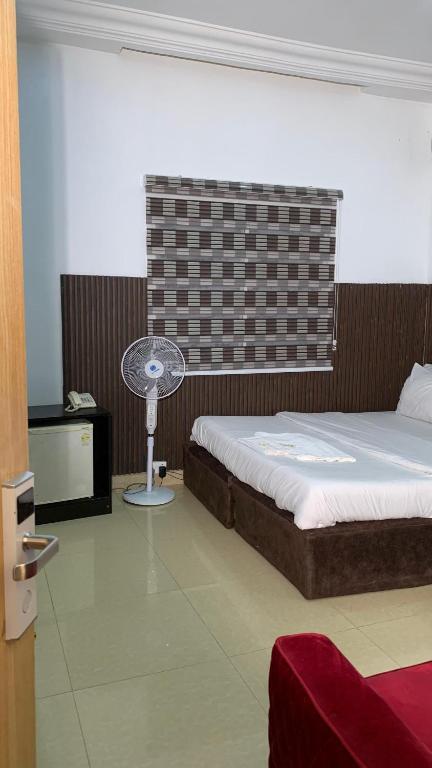 a bedroom with a bed and a fan in it at Halijomak Apartments in Abuja