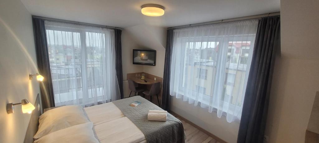 a bedroom with a bed and two large windows at Willa Wladek in Władysławowo