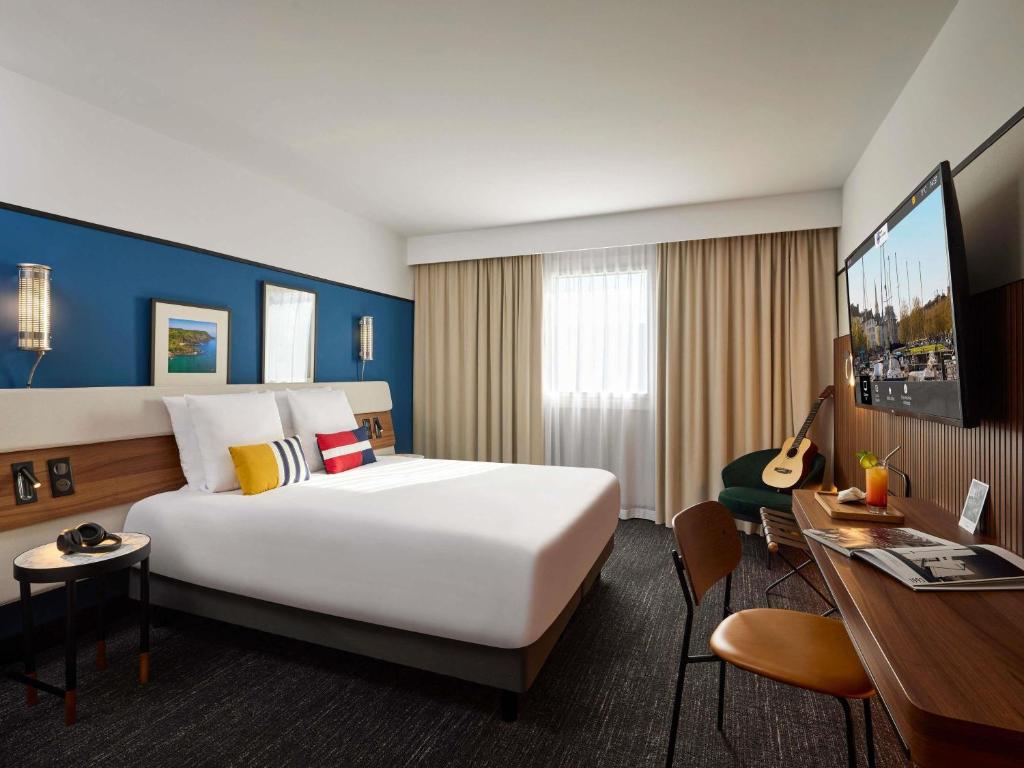 a hotel room with a large bed and a desk at Mercure Caen Centre Port De Plaisance in Caen