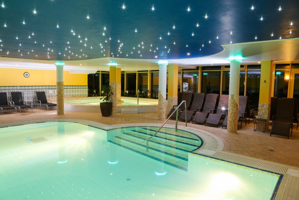 uma piscina no meio de um hotel com cadeiras em Calimbra Wellness Hotel Superior em Miskolctapolca