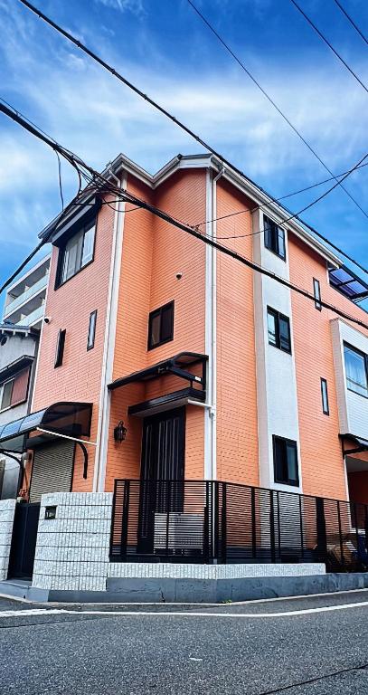 a orange and white building on the side of a street at guesthouse嵐 in Osaka