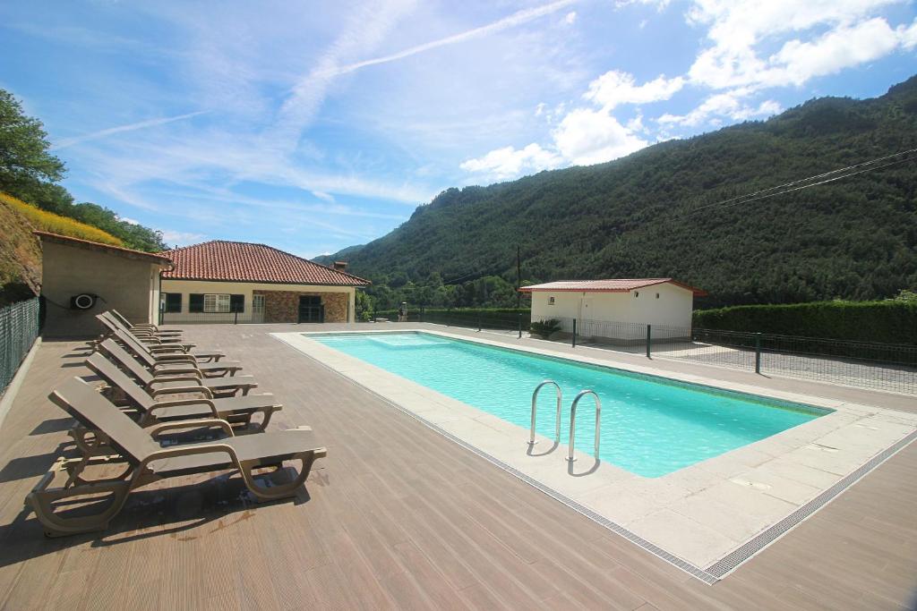 a swimming pool with lounge chairs next to a house at Paraíso do Gerês in Geres
