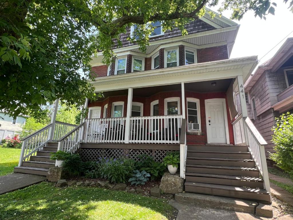 a red house with a white porch and stairs at Red Brick Inn - Walk to the Falls, the Casino and all Downtown Restaurants in Niagara Falls