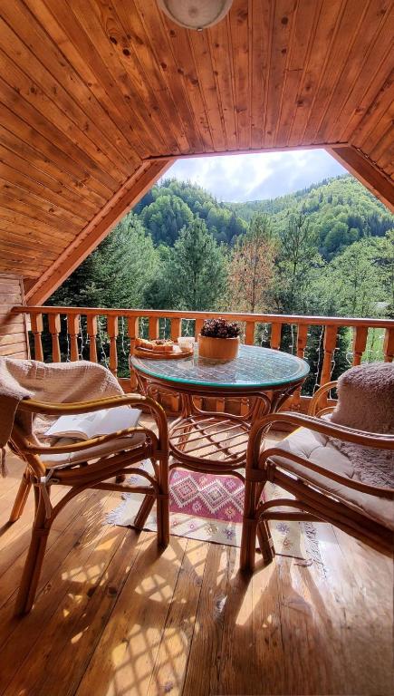 a room with a table and chairs on a porch at Cabana de la rau Satic in Sătic