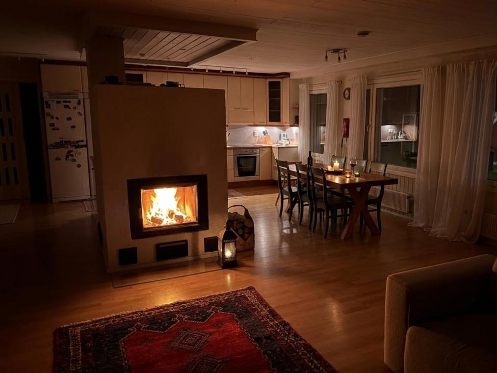 a living room with a fireplace and a dining room table at Red House at Kuusitie in Kittilä