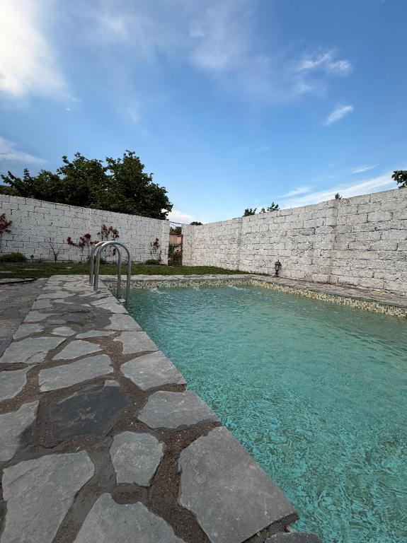 a pool of blue water next to a stone wall at Lisan VIllas in Nabran