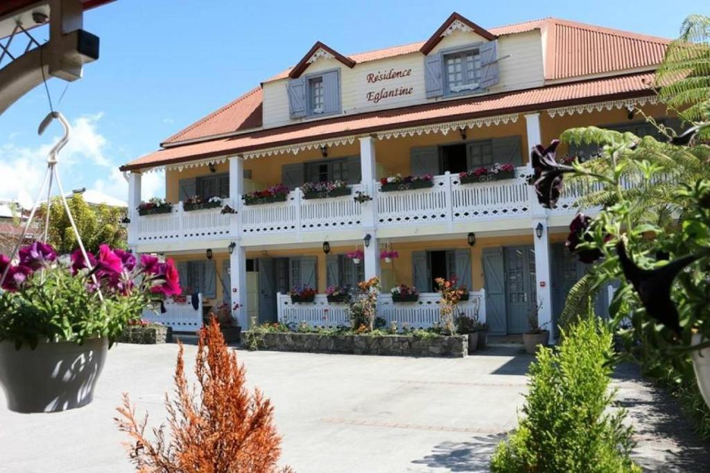 ein großes weißes Gebäude mit Blumen davor in der Unterkunft Résidence Eglantine in Cilaos