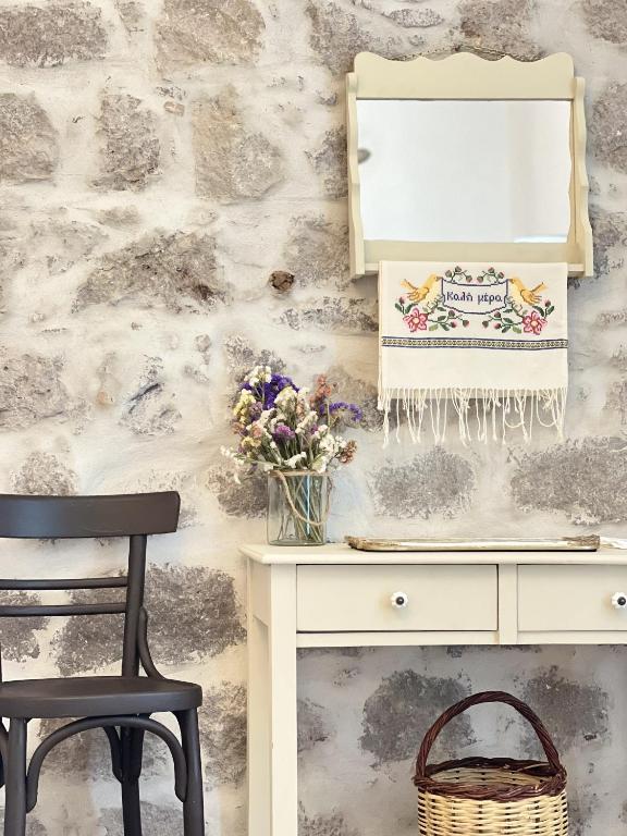 a desk with a vase of flowers next to a wall at Sokaki Patmos in Skala