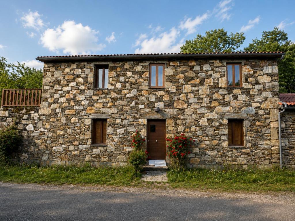 a stone building with a door and flowers in front at Casa das Minas in Zobra