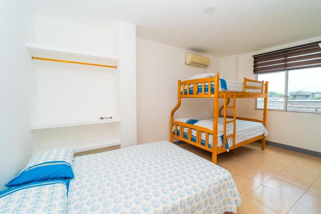 ein Schlafzimmer mit einem Bett, einem Etagenbett und einem Fenster in der Unterkunft Pangora, habitación privada de Flor de Lis Beach House in Playas