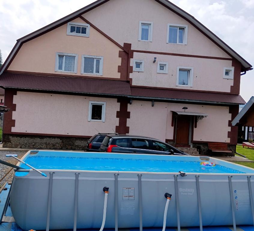 a house with a swimming pool in front of a house at "Різьб'ярська садиба" in Slavske
