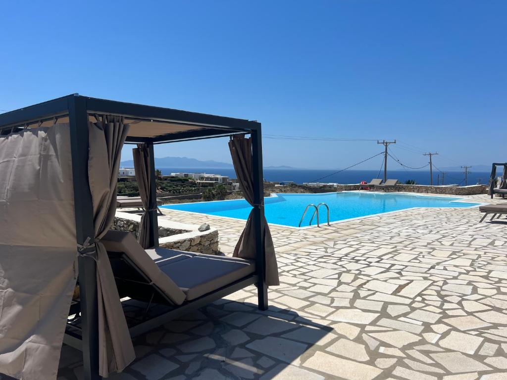 a chair in a gazebo next to a swimming pool at Rineia Complex by Live&Travel in Mikonos