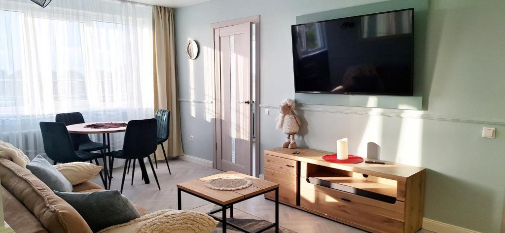 a living room with a couch and a tv on a wall at Fountain View 2 bedroom Apartment in Naujoji Akmenė