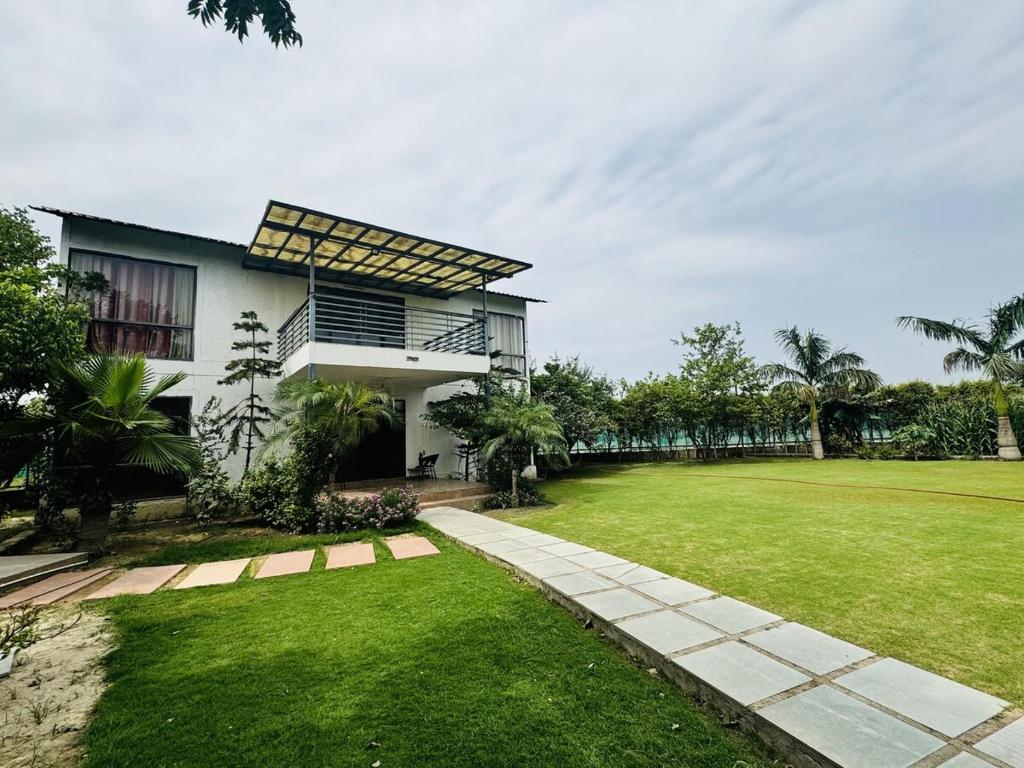 a house with a grassy yard next to a building at Rk farms in Noida