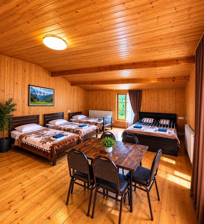 a room with two beds and a table and chairs at Daeli Hotel in Mestia