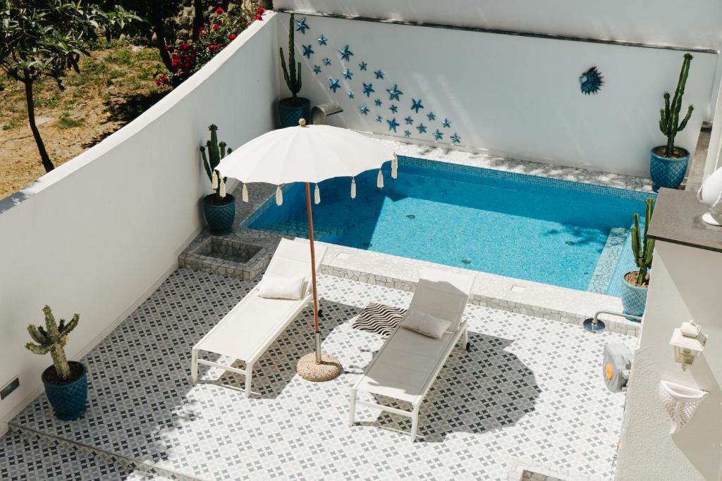 a swimming pool with two chairs and an umbrella at Queen Suite - Luxury Rooms in Forio d'Ischia