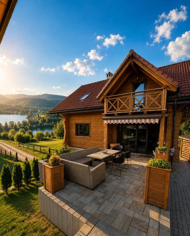 a house with a patio with a view of a lake at Łykolańczyk-Chatki z JACUZZI in Polańczyk