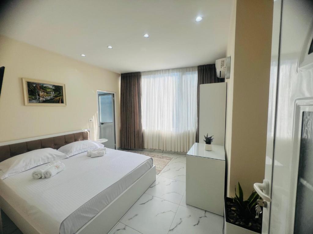 a bedroom with a white bed and a refrigerator at Bar Hotel Mokador in Shkodër