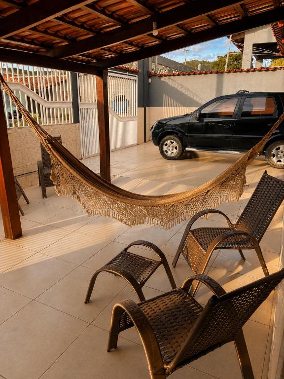 a hammock on a patio with two chairs and a car at Casa Chapadeira in Colinas Do Sul