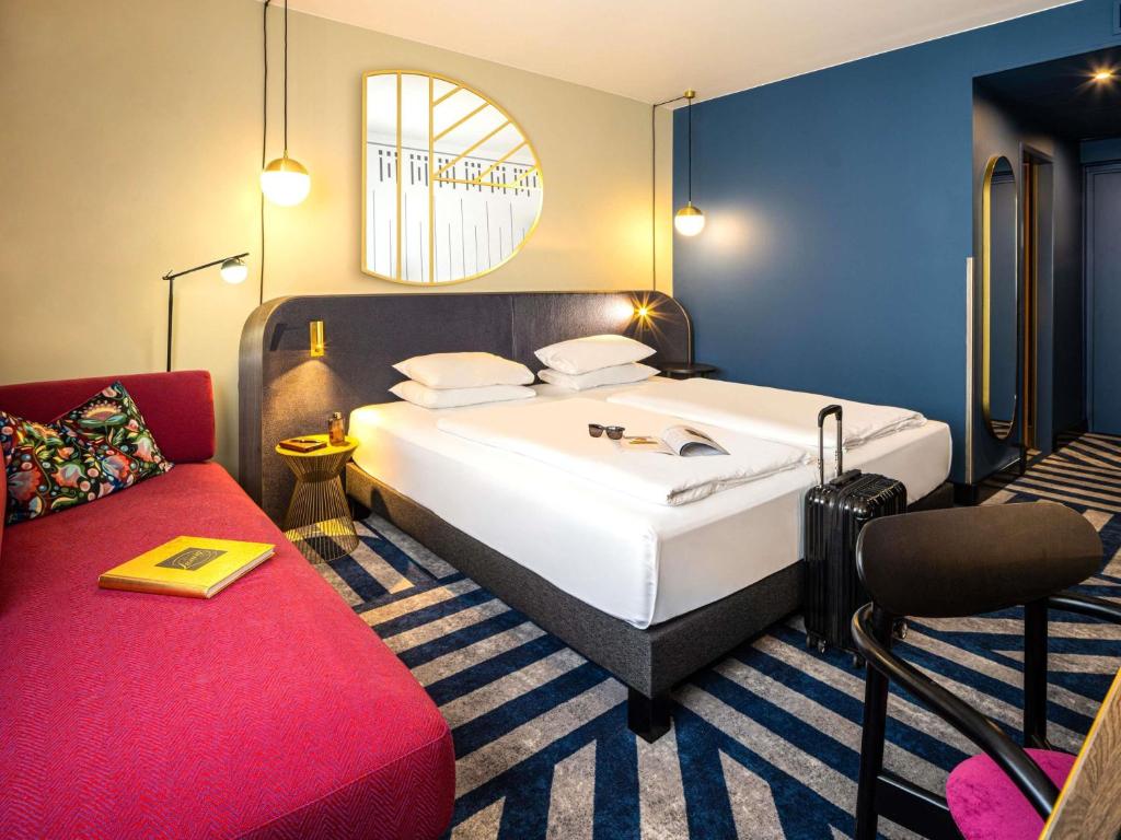a bedroom with a large bed and a red couch at Hotel Mercure Wien City in Vienna