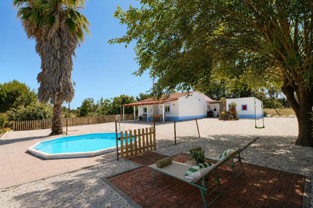 a swing and a chair next to a swimming pool at Chicas Country House in Amieira