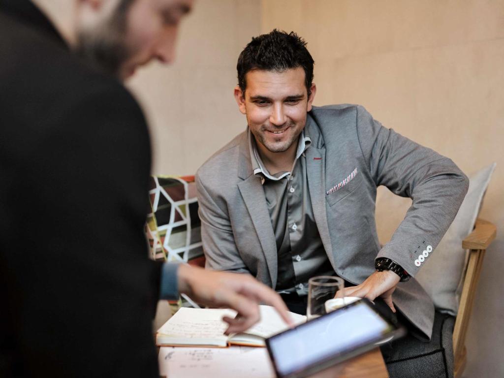 A seated guest works at a table with a tablet, papers and a drink.