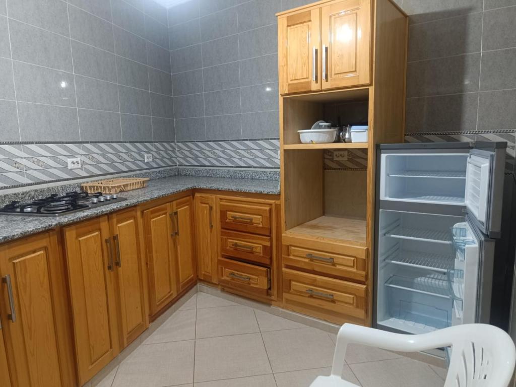 a kitchen with wooden cabinets and an empty refrigerator at Centre boukidan in Al Hoceïma