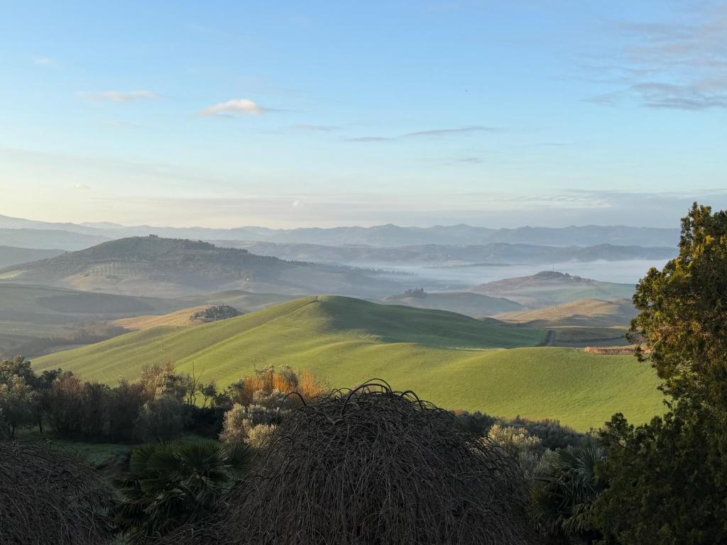 a view of a green field with mountains in the background at Le Guadalupe by Luigi in Volterra