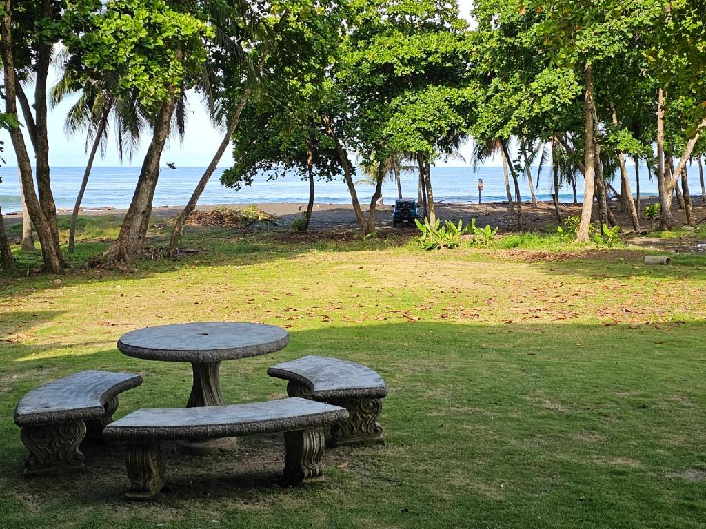 a picnic table and benches in a park near the ocean at Outback Hermosa in Playa Hermosa