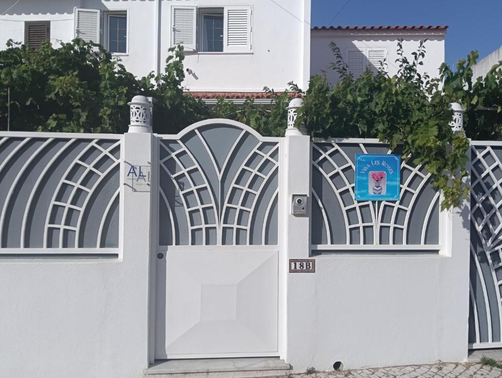 a white fence with an open door in front of a house at Vila les Roses Quartos Jardim e Montanha in Porches