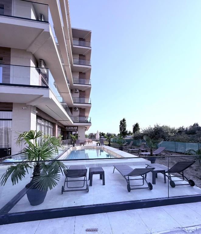 a large building with a swimming pool with chairs and a table at Alemar Mamaia Nord in Năvodari