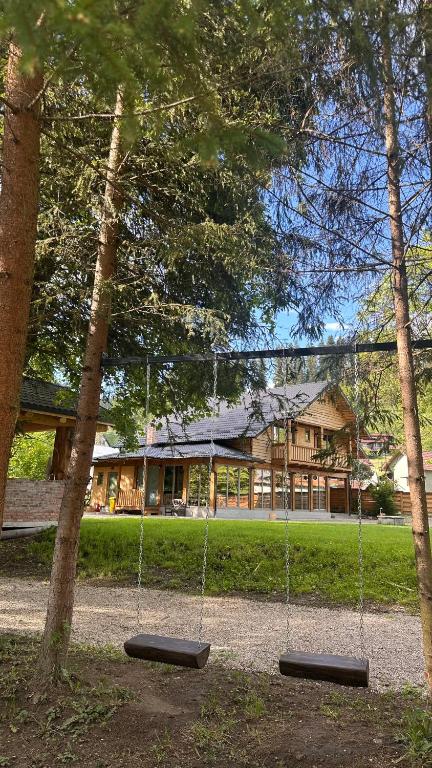 a swing in a park with a house in the background at Cabana Pârâul Lupilor in Răchitiş