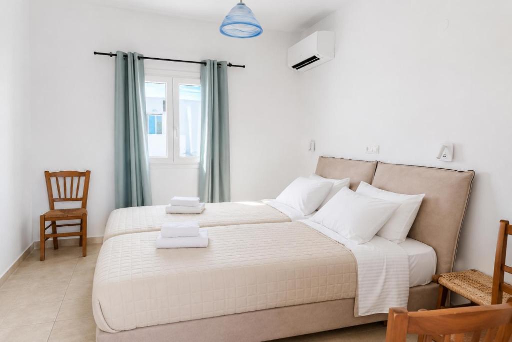 a bedroom with a large bed and a chair at Argo Rooms Antiparos in Antiparos
