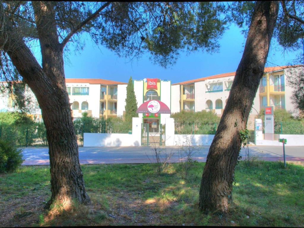 a hospital with two trees in front of a building at ibis Sète Balaruc les Bains Bien-être et Spa in Balaruc-les-Bains