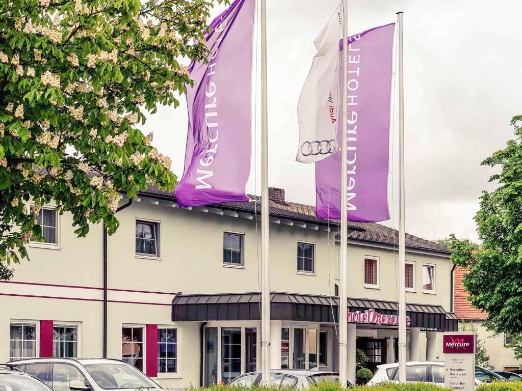 a building with purple and white flags in front of it at Mercure Hotel Ingolstadt in Ingolstadt