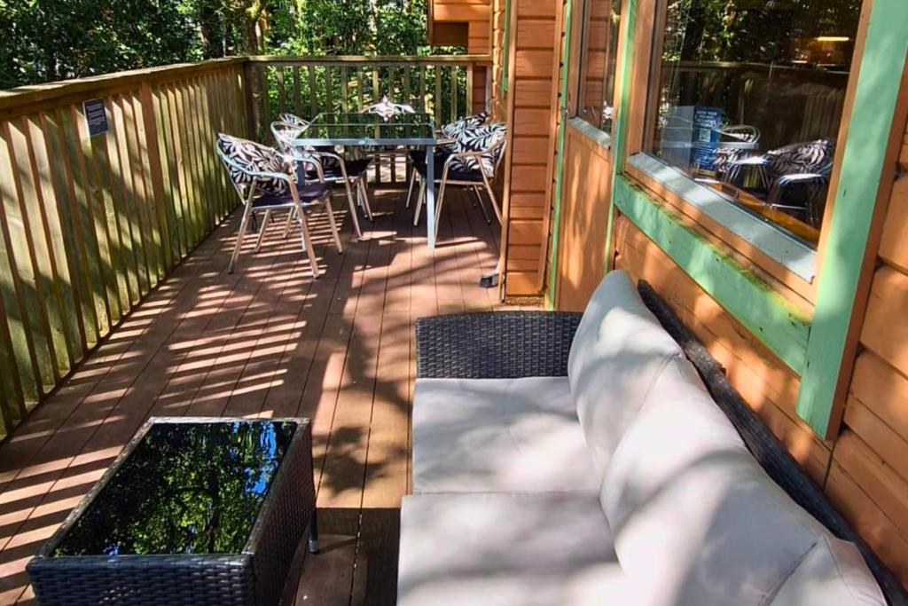 a patio with a table and chairs on a deck at Scandi Style Bracken Lodge with Private Decking Sleeps 6 in Chudleigh Knighton